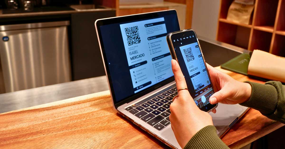 Person scannt einen digitalen Lebenslauf mit dem Smartphone von einem Laptopbildschirm.