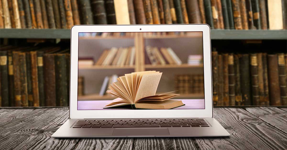 Laptop mit geöffnetem Buch auf dem Bildschirm vor einem Bücherregal – Symbol für den Wandel von analoger Literatur zur digitalen Kommunikation.