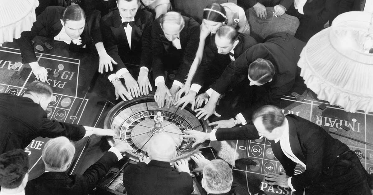 Gruppe elegant gekleideter Personen an einem Roulette-Tisch in einem historischen Casino