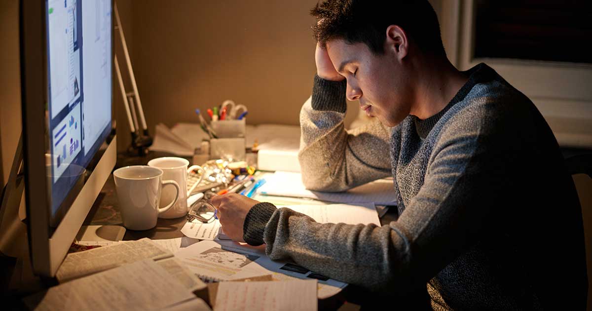 Student arbeitet nachts gestresst an seiner Abschlussarbeit am Computer