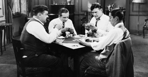 Vier Männer spielen an einem Tisch Poker – historische Schwarzweißaufnahme als Sinnbild für Risiko, Strategie und Schicksal.