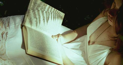 Frau liest ein Buch im Sonnenlicht – Symbol für Literatur, Verführung und Gedankenwelt