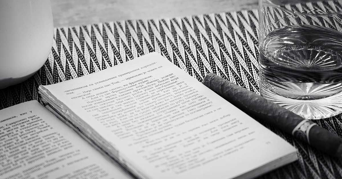 Aufgeschlagenes Buch mit Zigarre und Glas in einer ruhigen, symbolischen Schwarz-Weiß-Szene